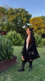 Ruana tejida a mano en color lila, confeccionada en lana merino. Presenta un diseño de punto con calados diagonales y terminación de flecos largos en el ruedo.