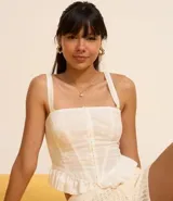 Blusa corset de laise blanca con bordado de flores, escote cuadrado, breteles y volados en el ruedo. Cierre frontal con corchetes.