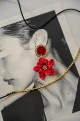 Par de aros colgantes con base circular negra con borde de strass y dije de flor negra con centro de strass.