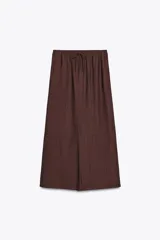 Falda midi marrón de tejido arrugado con cintura elástica ajustable con cordones y bolsillos laterales ocultos.