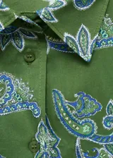Camisa verde con estampado paisley en tonos azules, de corte recto, manga larga con puños abotonados, cuello camisero y cierre frontal con botones.