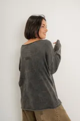 Buzo verde militar de tejido liviano con acabado gastado, corte oversize, cuello bote y mangas largas con hombro caído.