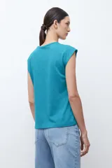 Remera verde petróleo con cuello redondo y abertura en forma de lágrima en el escote. Presenta un estampado geométrico en relieve y mangas cortas.