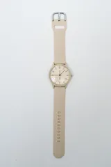 Reloj analógico con correa de silicona color rosa pálido y esfera blanca con números negros.