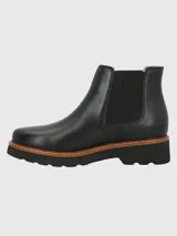 Botín Chelsea de cuero negro, estilo botín corto, con elásticos laterales y suela plataforma gruesa de goma con borde de cuero marrón y costura visible.