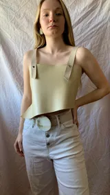 Top corto de ecocuero blanco con breteles anchos de ecocuero negro con textura de cocodrilo y hebillas metálicas.