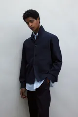 Sobrecamisa azul marino de corte recto, con cuello inglés, cierre frontal con botones, mangas largas con puños abotonados, dos bolsillos de parche en el pecho y canesú en la espalda.