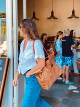 Bolso tote de cuero color marrón con asas trenzadas en marrón y rojo.