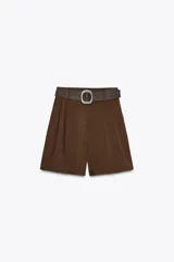 Bermuda color marrón chocolate de tiro alto con pinzas delanteras y cinturón trenzado. Bolsillos frontales. Cierre delantero con cremallera, botón interior y gancho.
