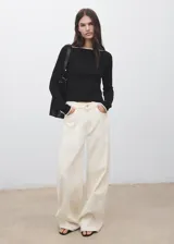 Top de manga larga negro, ajustado al cuerpo, con cuello barco y puños abotonados. Presenta ribetes en contraste de color claro en el cuello y los puños.