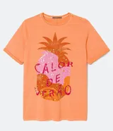 Remera color durazno de algodón con cuello redondo y mangas cortas. Presenta un estampado de piña con detalles de lentejuelas y la frase "Calor de Verão".