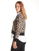 Cardigan de punto con estampado animal print de leopardo en tonos beige, negro y blanco, con escote en V y cuello con solapa. Presenta botones frontales y mangas largas con puño. Incluye una camisa blanca simulada debajo.