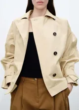 Anorak color beige, de corte oversize, con cuello camisero, cierre frontal con botones, bolsillos laterales con solapa y mangas largas con trabillas.