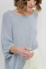 Sweater color crudo de tejido liviano con textura semi traslúcida, escote redondo y mangas amplias estilo murciélago.