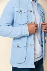 Cazadora blanca de lino con cuello camisero, cierre con botones, cuatro bolsillos frontales con solapa y corte entallado.