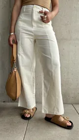 Pantalón de lino color crudo, de corte recto, con pinzas en la cintura y aberturas laterales en el ruedo.