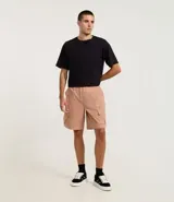 Bermuda masculina color beige, corte holgado, con cintura elástica ajustable con cordón, bolsillos laterales tipo cargo con cierre de cremallera y bolsillos traseros. Confeccionada en poliéster.