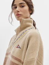 Sweater azul con cuello alto con medio cierre, textura tipo terciopelo y puños acanalados.