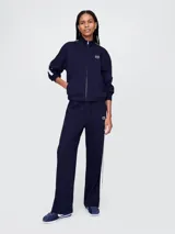 Campera deportiva Gap azul marino con cierre frontal, cuello alto y logo bordado en el pecho. Presenta dos líneas blancas verticales a lo largo de las mangas.