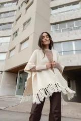 Ruana color crudo tejida en lana merino de 21 micras, con flecos en el borde inferior.
