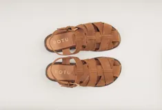 Sandalias bajas de cuero marrón con tiras entrecruzadas y hebilla dorada.