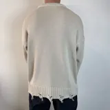 Sweater tejido color crema con cuello redondo y terminaciones con efecto desgastado y roturas.