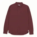 Camisa de popelina verde con cuello abotonado, cierre frontal con botones, bolsillo de parche en el pecho izquierdo, mangas largas con trabillas para enrollar y dobladillo camisero.