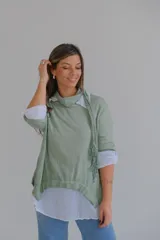 Sweater verde con cuello alto, mangas 3/4 y bajo asimétrico. Incluye una camisa blanca de mangas largas y una bufanda de encaje verde.