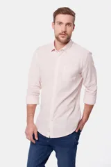 Camisa de lino color beige, de manga larga, con cuello clásico y bolsillo en el pecho.