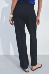 Pantalón de vestir azul marino de lana, con tiro bajo, cintura con trabillas, bolsillos laterales, raya planchada y cierre frontal con cremallera, botón y gancho metálico.