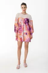 Vestido corto con vuelo de satén con maxi estampado floral combinado con organza semitransparente con líneas en el canesú. Tiene manga larga abullonada y tiene lazo en la espalda para anudar.