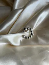 Aro tipo earcuff plateado con bolitas de diferentes tamaños. Se coloca a presión en el cartílago de la oreja.