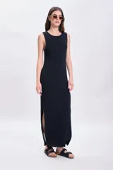 Vestido largo de punto negro con cuello redondo y sin mangas. Tiene corte recto y aberturas laterales en el ruedo.