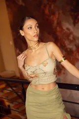 Top color verde con estampado de flores naranjas, escote corazón, fruncido y espalda con tiras regulables.