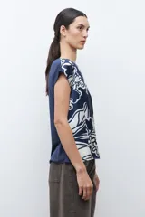Blusa de manga corta con cuello redondo, confeccionada en tela satinada con estampado abstracto en azul marino y blanco.