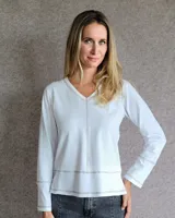 Remera blanca de manga larga con cuello en V y detalle de pespuntes en color tostado.