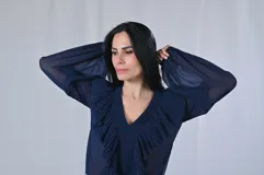 Camisa color verde lima de mangas largas con volados plisados en el frente y cuello en V.