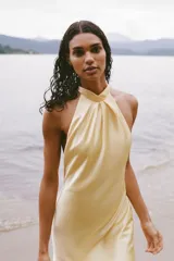 Vestido midi de satén color amarillo pálido, con cuello halter y espalda descubierta.