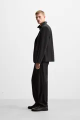Blazer negro de lana con cuello de solapa de muesca, corte recto, manga larga con puños abotonados, bolsillos de vivo en el pecho y de solapa en la cadera, abertura en la parte posterior y cierre frontal con botones. Colección Origins.