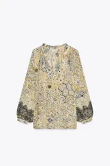 Blusa estampada con hilo metalizado, cuello redondo con volante, escote pico y manga larga abullonada.