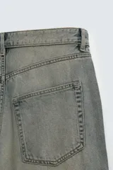 Pantalón de jeans de algodón, corte baggy fit, tiro medio, con efecto lavado en tonos grises y verdes. Presenta cinco bolsillos y cierre frontal con cremallera y botón.