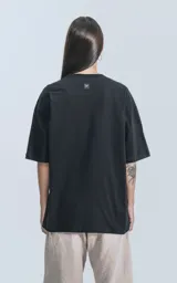 Remera negra de corte crop y calce oversize, con hombros caídos y cuello redondo.