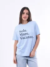 Remera negra de algodón con cuello redondo y mangas cortas. Estampado frontal con la frase "World Tour Vacation State of Mind" en letras de colores y un pequeño dibujo de una palmera.
