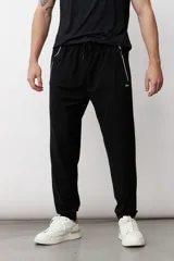 Pantalón de jogging negro con cintura elástica ajustable con cordón, bolsillos laterales con cierre y logo pequeño en la pierna izquierda.