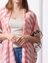 Kimono tejido con estampado abstracto en tonos beige, blanco y negro. Tiene mangas amplias estilo japonés y terminación de ruedo con borlas.