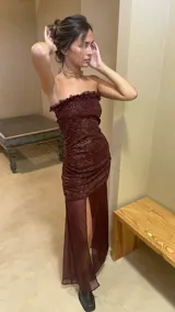 Vestido strapless color borgoña con frunces y falda transparente con tajo lateral.
