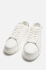 Zapatillas deportivas blancas con detalle en color gris en el talón y suela con plataforma.