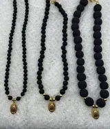 Set de tres collares de cuentas de piedra volcánica negra de diferentes tamaños, con dije dorado de la virgen.