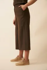 Pantalón palazzo color beige, de tiro alto, con bolsillos laterales y largo a la pantorrilla.