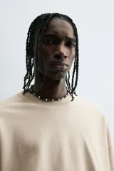 Camiseta color beige de corte holgado, cuello redondo y manga corta.